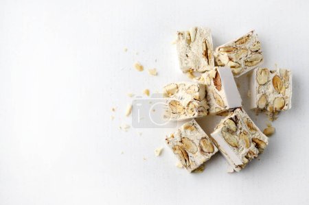 Téléchargez les photos : Torrone - soft Italian nougat with almonds isolated on white background. Holiday season. Copy space. - en image libre de droit