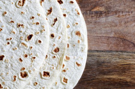 Photo for Close-up of Italian piadina isolated on wooden background. Flatbreads, tortilla bread, romagnola piadina. Copy space. Directly above. - Royalty Free Image