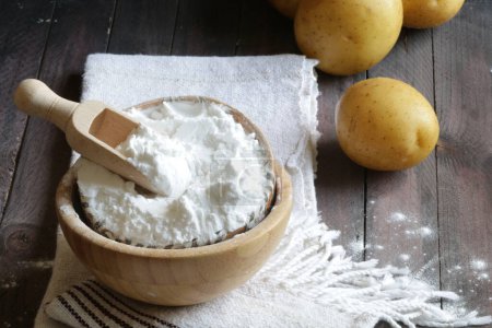 Potato starch and potatoes isolated on  wooden background. Close-up, copy space.