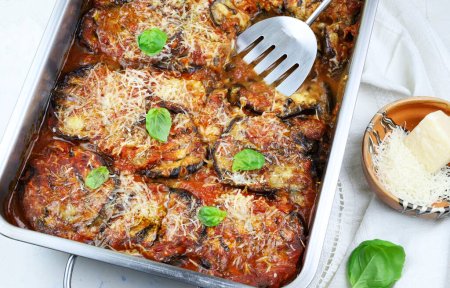 Concept of Italian food. Baked eggplant with cheese and tomato sauce on white background. Parmigiana melanzane. Directly above.