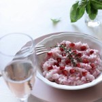 Delicious risotto with pomegranate on dark background. Vegetarian or vegan food. Directly above. Copy space.