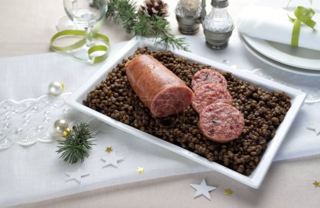 Photo for An Italian New Year Eve table. Cotechino with lentil served on plate. Family gathering concept. Holiday season. Close-up. - Royalty Free Image