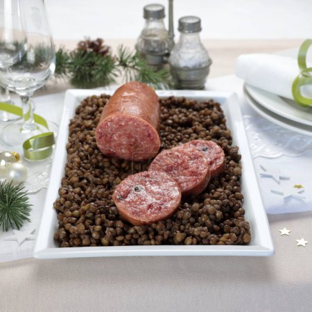 Photo for An Italian New Year Eve table. Cotechino with lentil served on plate. Family gathering concept. Holiday season. Close-up. - Royalty Free Image