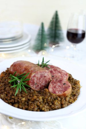 Photo for Cotechino with lentils served on a plate and a glass of red wine isolated on white background. Christmas decorations. Christmas holiday. Italian food concept. Overhead view. - Royalty Free Image