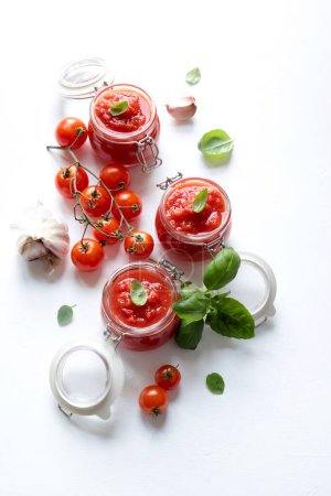 Klassisch hausgemachte italienische Tomatensauce mit Basilikum für Pasta oder Pizza in einem Glas auf weißem Hintergrund. Italienisches Lebensmittelkonzept. Aus der Vogelperspektive. Kopierraum.
