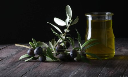 Téléchargez les photos : Branches d'olives et huile d'olive fraîche isolées sur fond noir. Espace de copie. Gros plan. - en image libre de droit