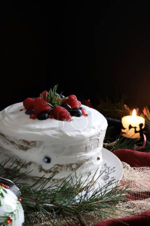 Traditional Italian Christmas pandoro or panettone cake with cream and wild berries on black background with Christmas decoration. Christmas and New Year traditions concept.