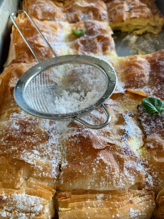 Greek cuisine. Homemade traditional greek Bougatsa, phyllo pastry filled with cheese and sprinkled with powdered sugar. Directly above.