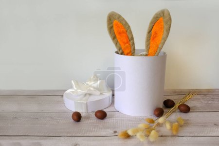 Téléchargez les photos : Oeufs de Pâques et un panier blanc avec des oreilles de lapin - en image libre de droit