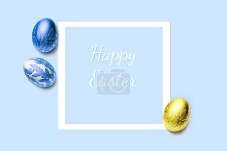 Téléchargez les photos : Cadre et trois œufs de Pâques décorés avec de l'or et de la couleur bleue sur fond bleu. Joyeux titre de Pâques. Pose plate, vue du dessus, espace de copie. - en image libre de droit