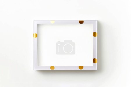 Téléchargez les photos : Maquette cadre blanc sur mur blanc à pois dorés. Minimalisme - en image libre de droit