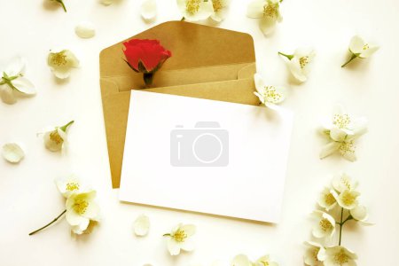 Téléchargez les photos : Carte blanche vierge avec enveloppe en papier kraft brun et jasmin, fleurs roses - en image libre de droit