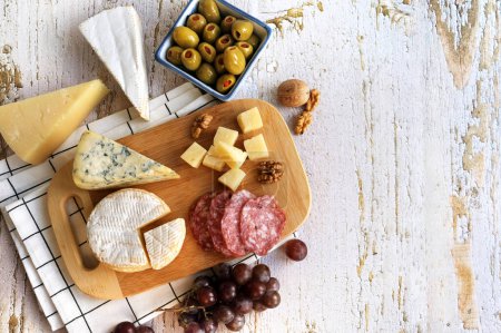 Téléchargez les photos : Différents types de fromages avec raisin, olives et noix sur fond blanc - en image libre de droit