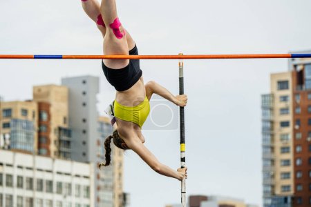 Téléchargez les photos : Chelyabinsk, Russie - 23 juin 2022 : saut à la perche des athlètes féminines en gros plan sur fond de bâtiments - en image libre de droit
