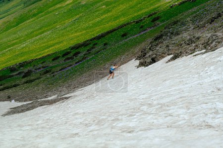 Photo for Arkhyz, Russia - July 2, 2022: female athlete walking snowy uphill in Arkhyz X Run - Royalty Free Image