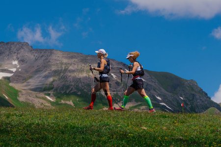 Photo for Arkhyz, Russia - July 3, 2022: two female athlete walking mountain trail in Arkhyz X Run - Royalty Free Image