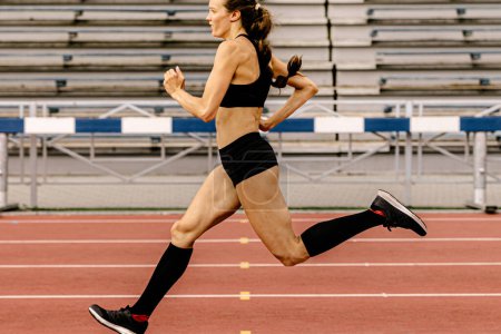 Foto de Atleta femenina corriendo sprint en pista de estadio - Imagen libre de derechos