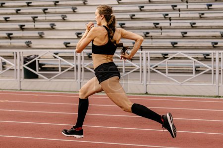 Foto de Corredor femenino corriendo sprint en pista de estadio - Imagen libre de derechos