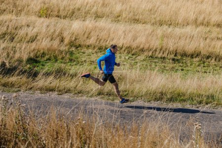 Téléchargez les photos : Male runner running road in field of dry grass - en image libre de droit