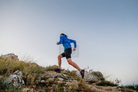 Photo for Male runner running uphill in blue sky background - Royalty Free Image
