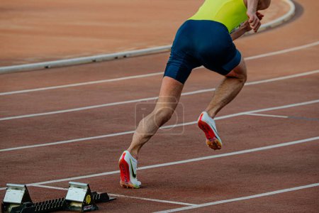 Téléchargez les photos : Chelyabinsk, Russia - June 4, 2022: runner in Nike Zoom spikes shoes running from starting blocks during UFD Athletics Championship - en image libre de droit