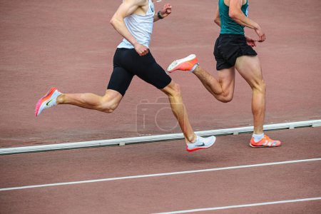 Téléchargez les photos : Chelyabinsk, Russia - June 5, 2022: two male runners in spikes shoes Nike and Adidas running middle distance at stadium during UFD Athletics Championship - en image libre de droit