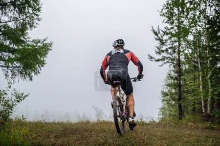 Téléchargez les photos : Retour athlète cycliste en vélo de montagne sur le sentier forestier. jambes sales, corps et vélo. compétition transnationale - en image libre de droit