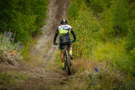 Foto de Espalda atleta masculino en bicicleta de montaña paseo sendero forestal. suciedad en pies y cuerpo. competencia ciclista entre países - Imagen libre de derechos