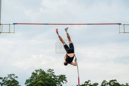 Photo for Back male athlete pole vault in sky background, Nike spikes shoes and socks, summer sports games - Royalty Free Image