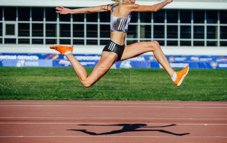 Photo for Female athlete tripl jump in competition athletics, spikes shoes for jumping, slip and sporty bustier Adidas, sports photo - Royalty Free Image