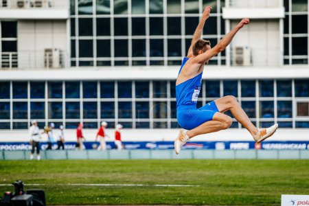 Foto de Atleta masculino salto de longitud en el atletismo de competición, zapatos de espigas para saltar Adidas y medias Nike, foto deportiva - Imagen libre de derechos