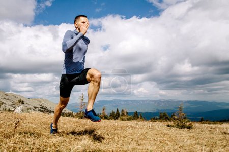 Foto de Hombre atleta corriendo en la meseta de montaña, fondo cielo azul y nubes, foto deportiva - Imagen libre de derechos