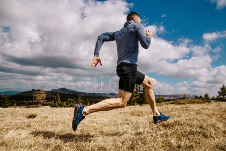 Téléchargez les photos : Athlète homme coureur cross country course sur herbe sèche, été en plein air, photo de sport - en image libre de droit