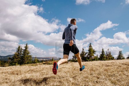 Téléchargez les photos : Dos coureur homme cross country course sur herbe sèche, été en plein air, photo de sport - en image libre de droit