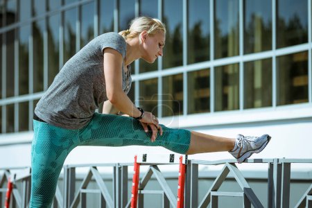 Foto de Mujer atleta haciendo ejercicio de estiramiento, inclinación hacia adelante a la pierna, calentamiento antes del entrenamiento de atletismo - Imagen libre de derechos