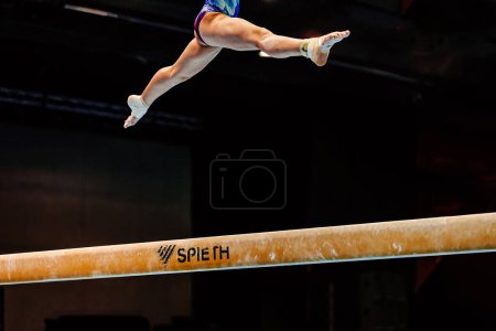 Photo for Female gymnast exercise split jump in balance beam on black background, apparatus Spieth balance beam, summer sports games - Royalty Free Image