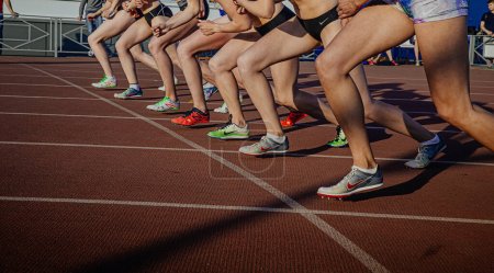 Photo for Legs female athletes in running spikes Nike and New Balance on starting line of middle distance race, olympic summer sports - Royalty Free Image