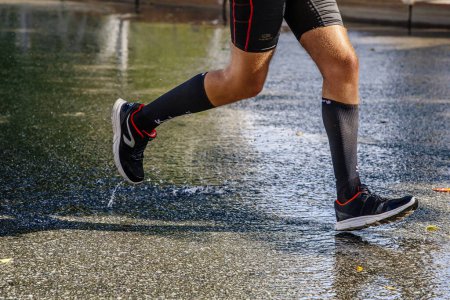 Photo for Male runner irunning on water road in city marathon race, shoes, compression socks and tights french running brand Kalenji - Royalty Free Image