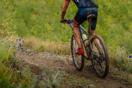 Foto de Ciclista de montaña masculino montando en bicicleta de cross-country, gotas sucias en bicicleta y ropa, carrera en camino nublado - Imagen libre de derechos
