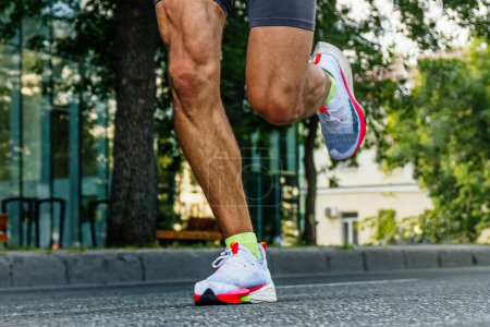 Foto de Close-up piernas corredor masculino corriendo carrera maratón de la ciudad, atleta trotando en el camino de asfalto, juegos de deportes de verano - Imagen libre de derechos