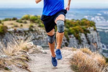 Beine Läufer Mann in Knieschoner läuft Bergweg, Schutz Knie Ärmel nach Verletzung an Stabilisierungsbeinen