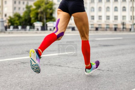legs female runner in compression socks and kinesio tape on knee to running marathon, woman jogger run city race