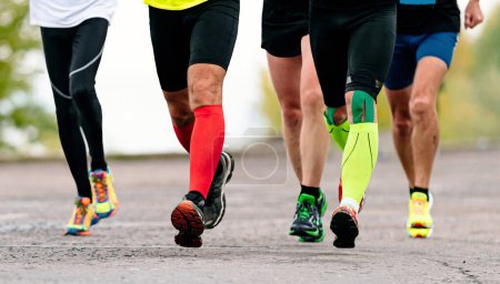 Photo for Group runners athletes running marathon race, front view legs jogger in compression socks and kineso tape knee - Royalty Free Image