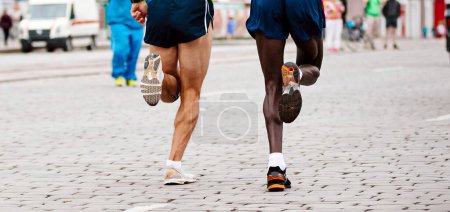Foto de Dos corredores kenianos y europeos corriendo maratón, carrera de jogger campeonatos del mundo, suelas zapatillas de running - Imagen libre de derechos