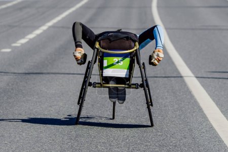 Téléchargez les photos : Para athlète en fauteuil roulant course de marathon sur route, passage supérieur en montée, compétition de para athlétisme - en image libre de droit
