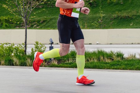 Foto de Corredor masculino en calcetines de compresión corriendo distancia maratón en el parque de la ciudad, competición deportiva de resistencia - Imagen libre de derechos