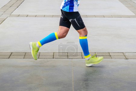 Téléchargez les photos : Jambes athlète coureur en chaussettes de compression course marathon distance, lumineux et coloré vêtements de sport - en image libre de droit