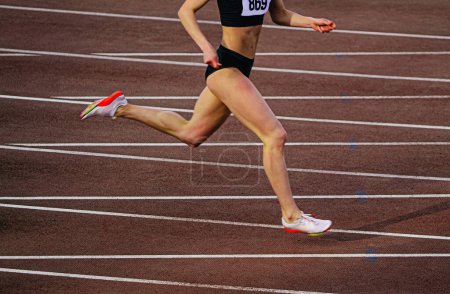 Photo for Female athlete running on red track stadium, summer athletics championships, geometric white lines - Royalty Free Image