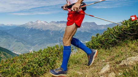 Téléchargez les photos : Athlète coureur en chaussettes de compression course trail montagne dans les mains bâtons de trekking, compétition de course skyrunning - en image libre de droit