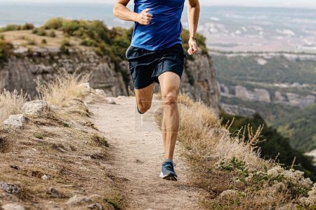 rangy male runner run on mountain trail, muscular legs man jogger athlete running narrow path